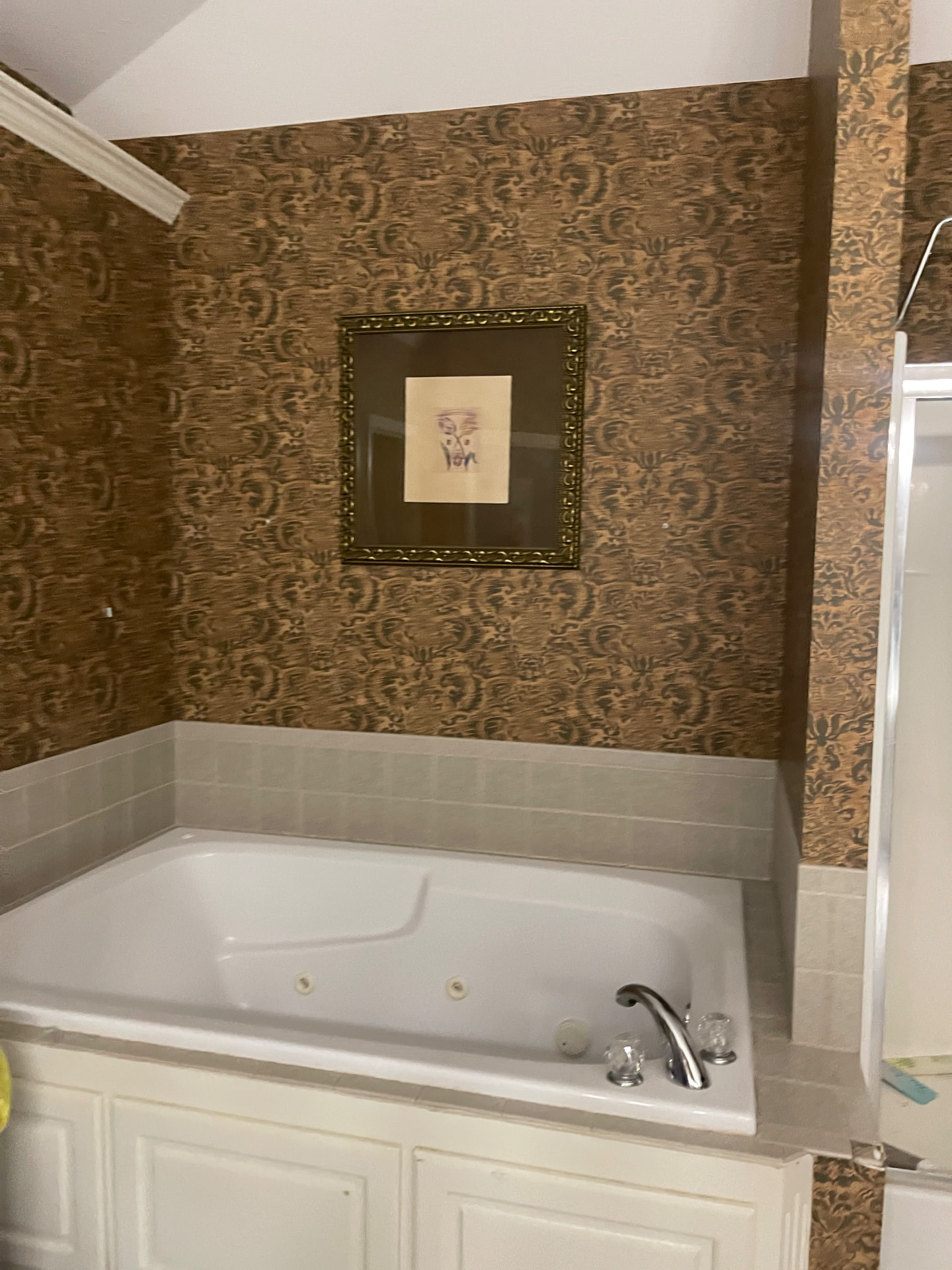 Dated jetted tub and wallpaper before the bathroom remodel